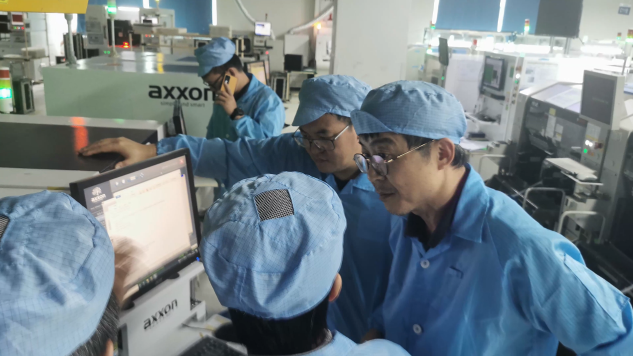 Axxon Mycronic staff gathered around a machine