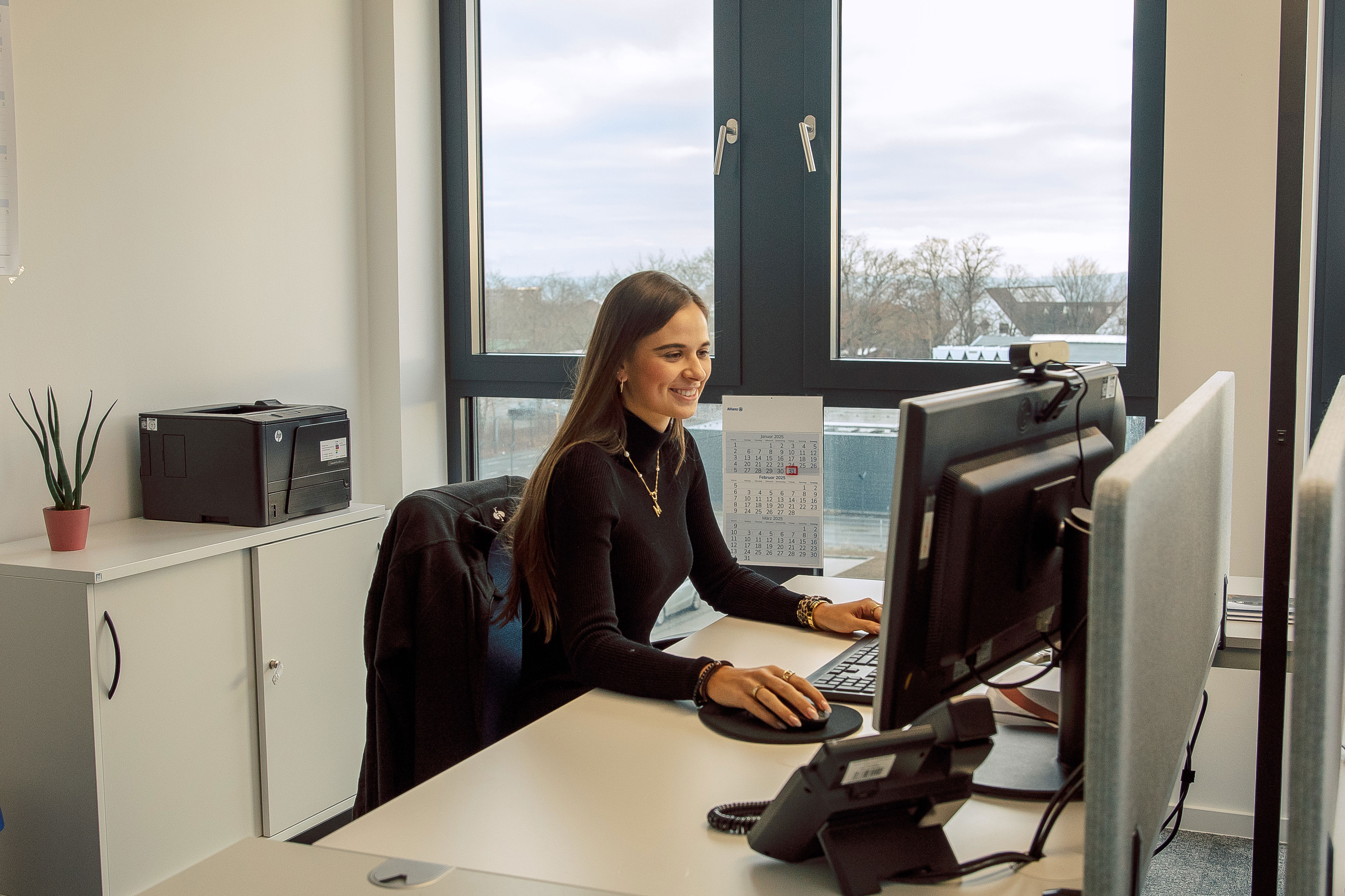 A woman working in front of computer in a brightly lit and pleasant office space
